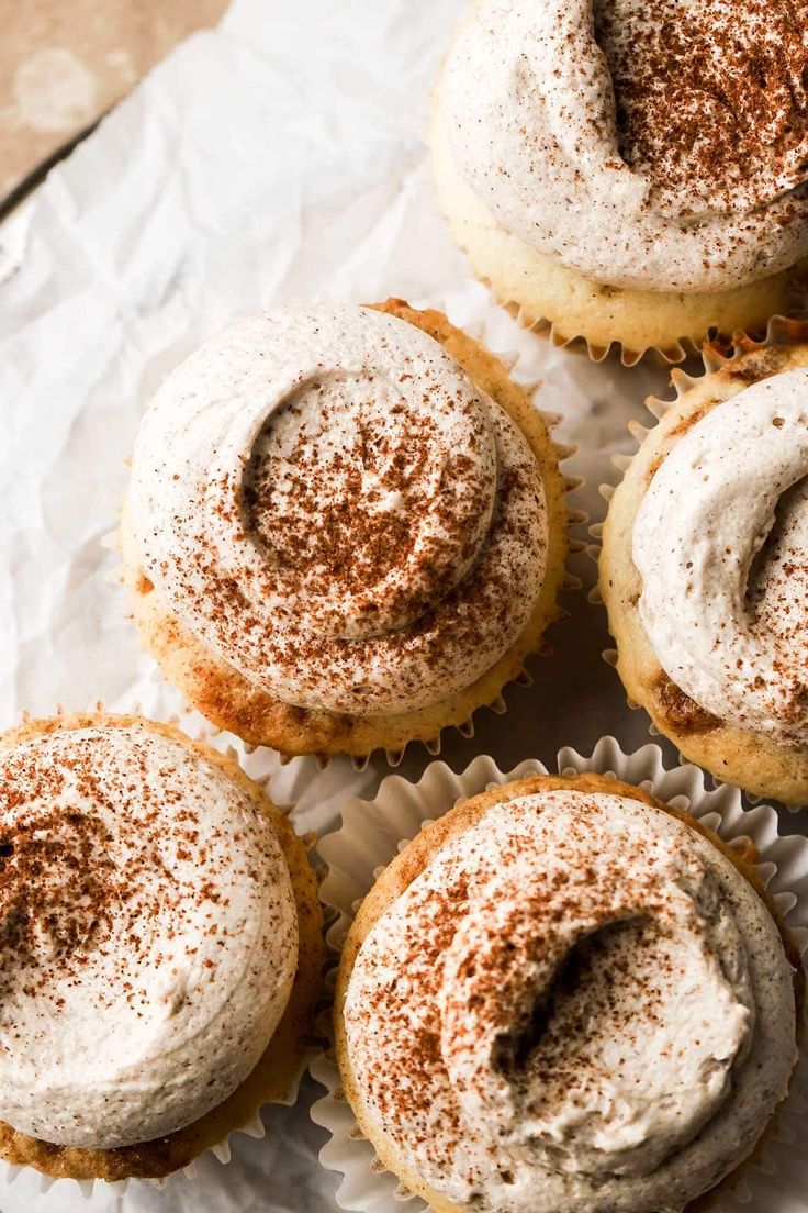 several cupcakes with white frosting and cinnamon sprinkles