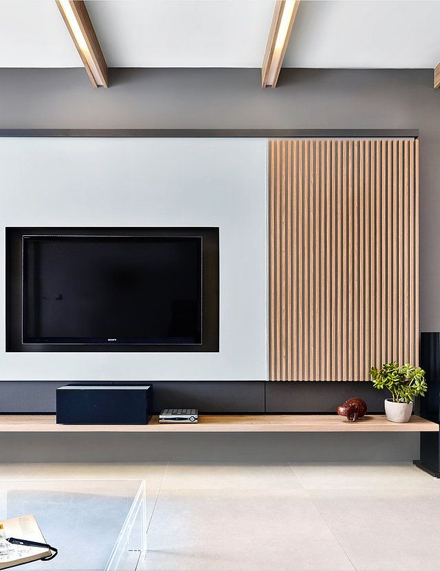 a flat screen tv sitting on top of a wooden shelf in front of a white wall