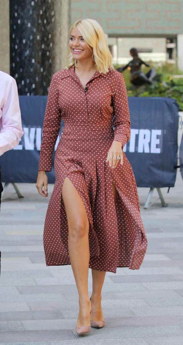 a woman in a red dress walking down the street with her legs crossed and wearing high heels