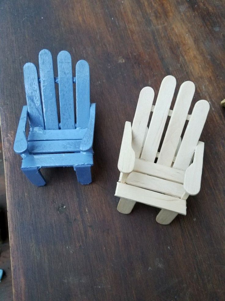 two small wooden chairs sitting on top of a table next to each other, one blue and the other white