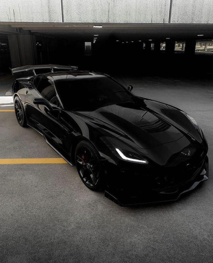 a black sports car is parked in a parking lot with yellow lines on the ground