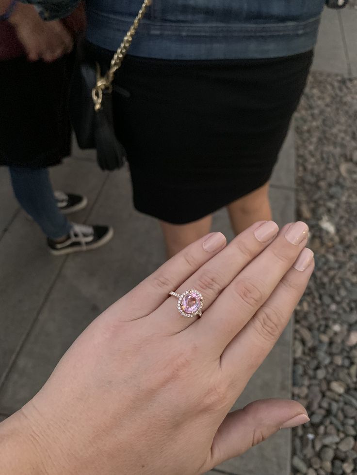 a woman's hand with a pink diamond ring on top of her left hand