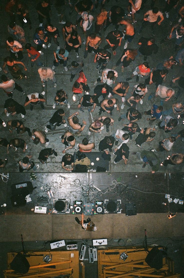 an overhead view of many people sitting and standing in front of a wall with electronic equipment on it