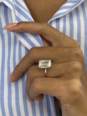 a close up of a person wearing a ring with a baguette on it