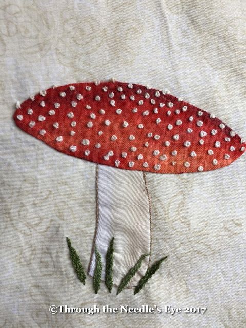 a red mushroom with white dots on it's head sitting on a piece of fabric