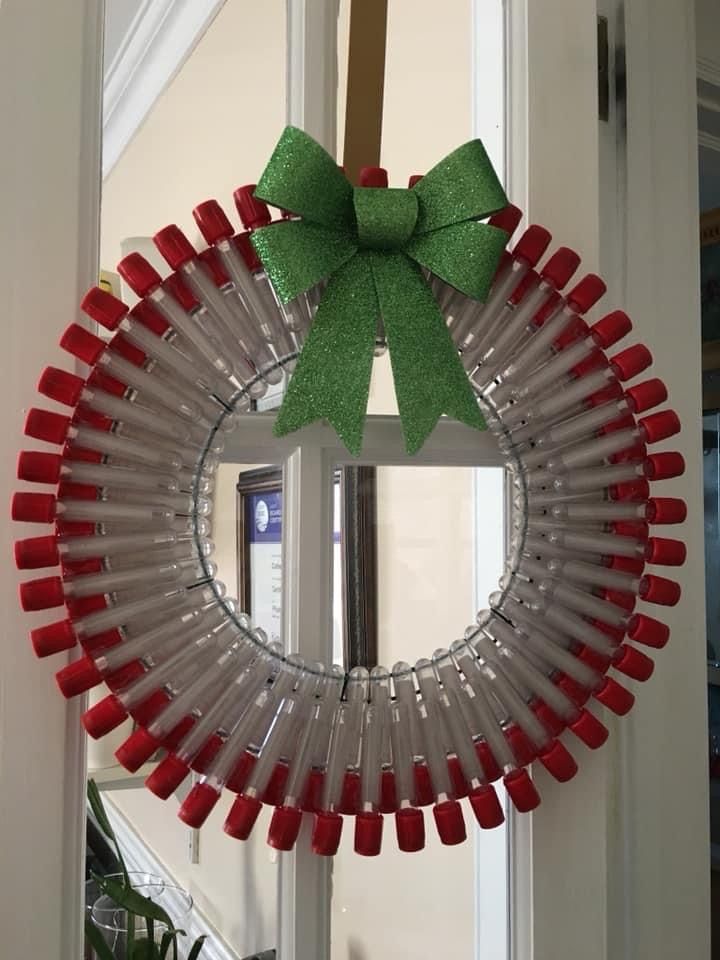 a wine bottle wreath with a green bow hanging from the front door to hang it