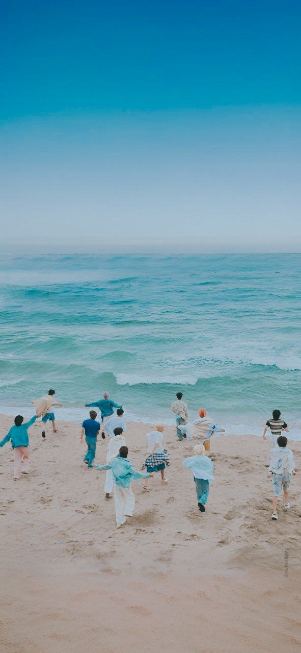 many people are on the beach playing in the sand with an ocean view behind them