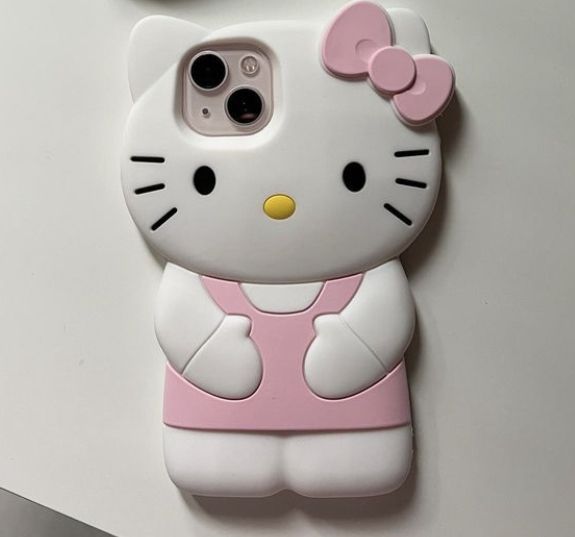 a hello kitty phone case sitting on top of a white table next to a cell phone