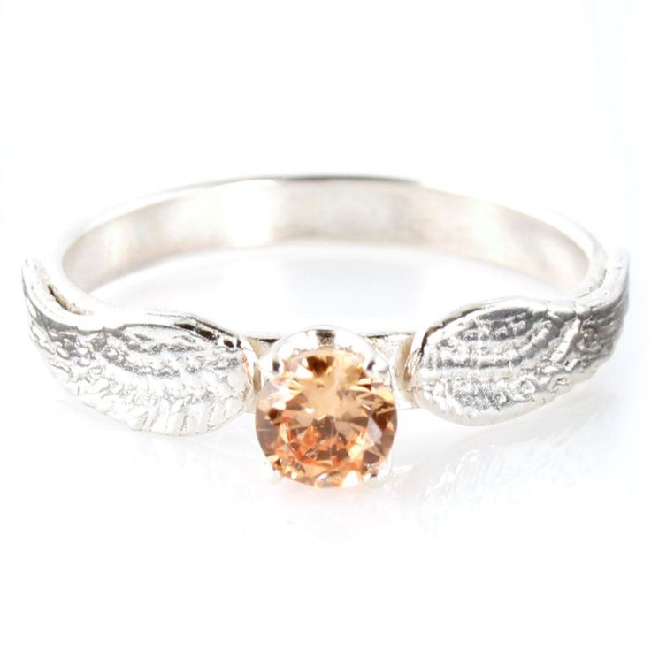 a white gold ring with an orange diamond in the center and leaves on it's sides