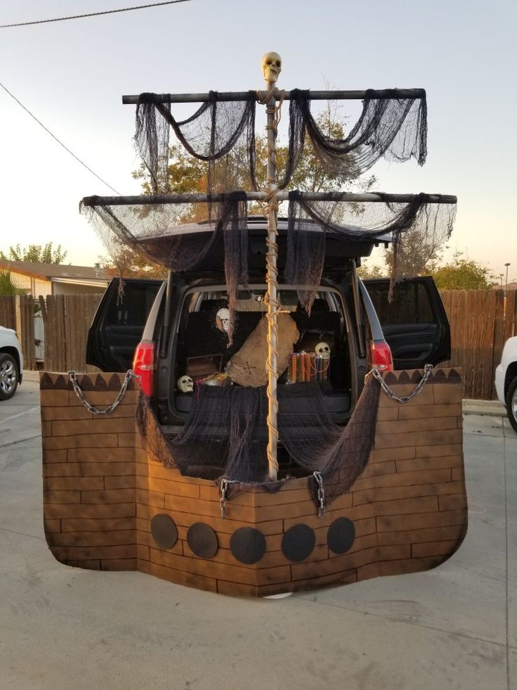 a pirate ship made out of bricks and rope is parked in a parking lot next to a white van