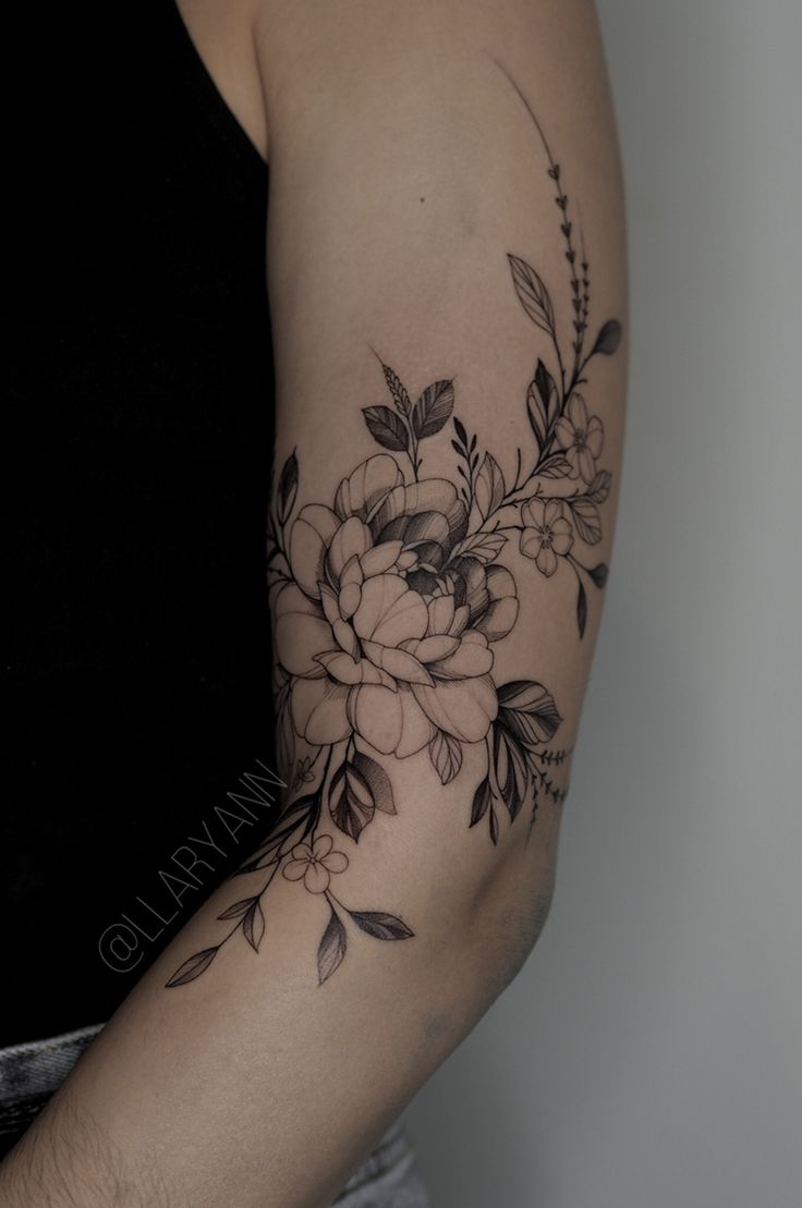 a woman's arm with flowers and leaves tattooed on the left side of her arm