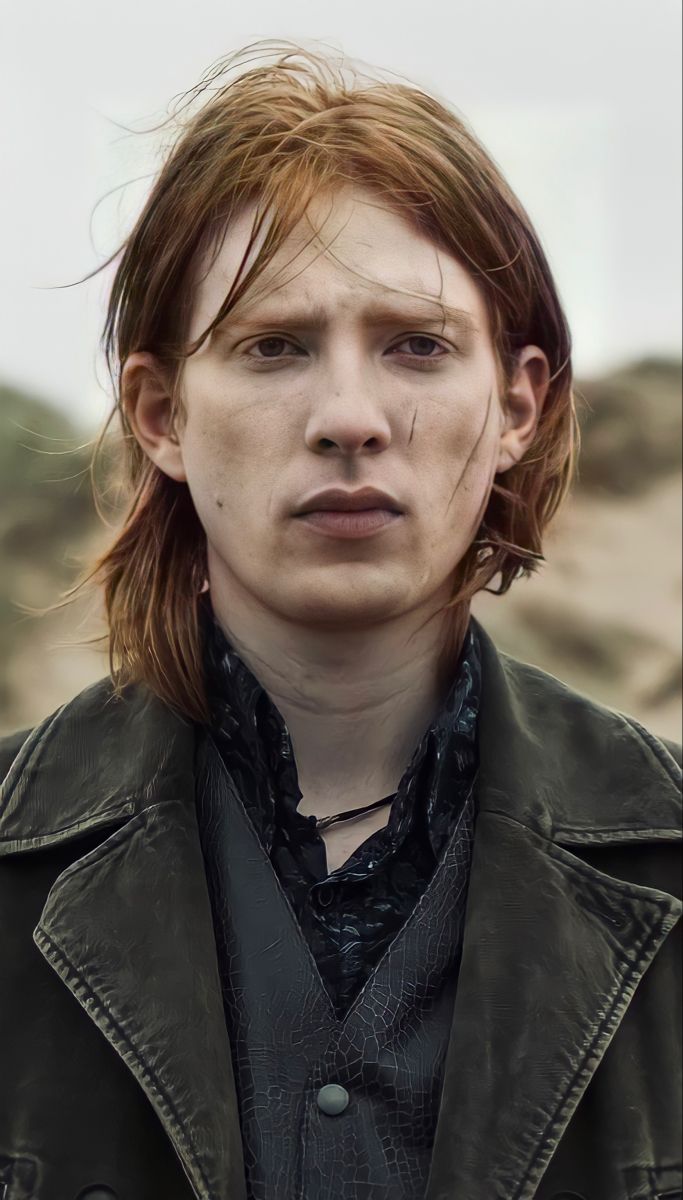 a young man with long hair wearing a leather jacket