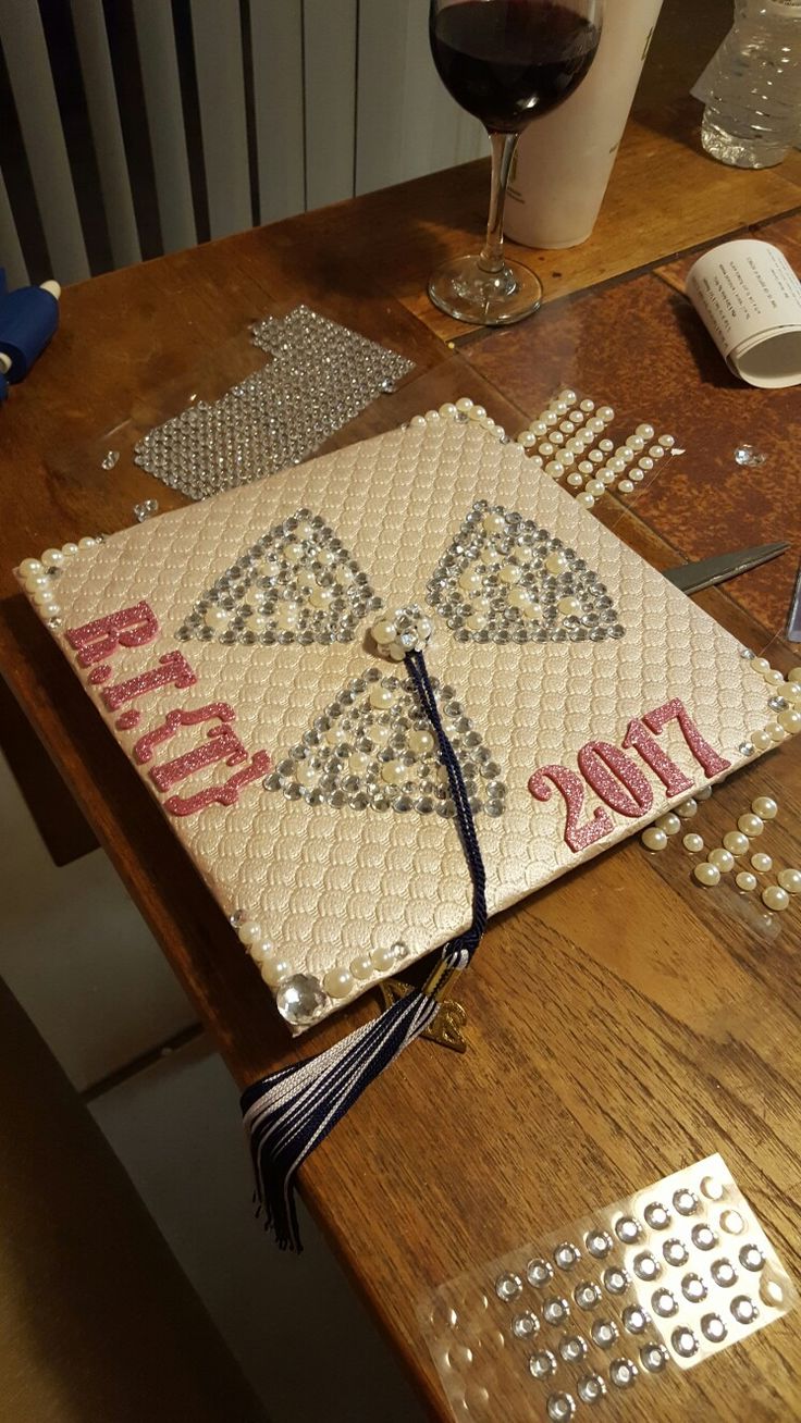 a table topped with a book covered in diamonds and pearls next to a glass of wine