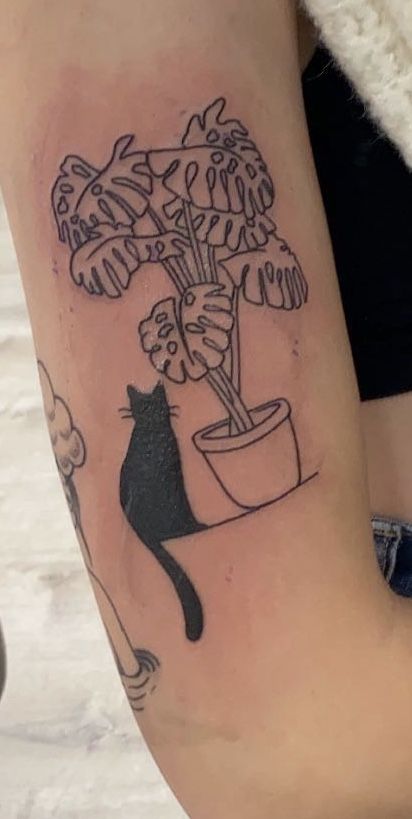 a woman's arm with a cat and potted plant on it