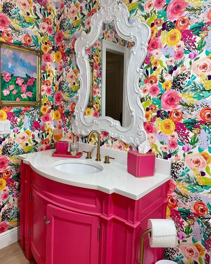 a bathroom with floral wallpaper and bright pink sink vanity, mirror and toilet paper