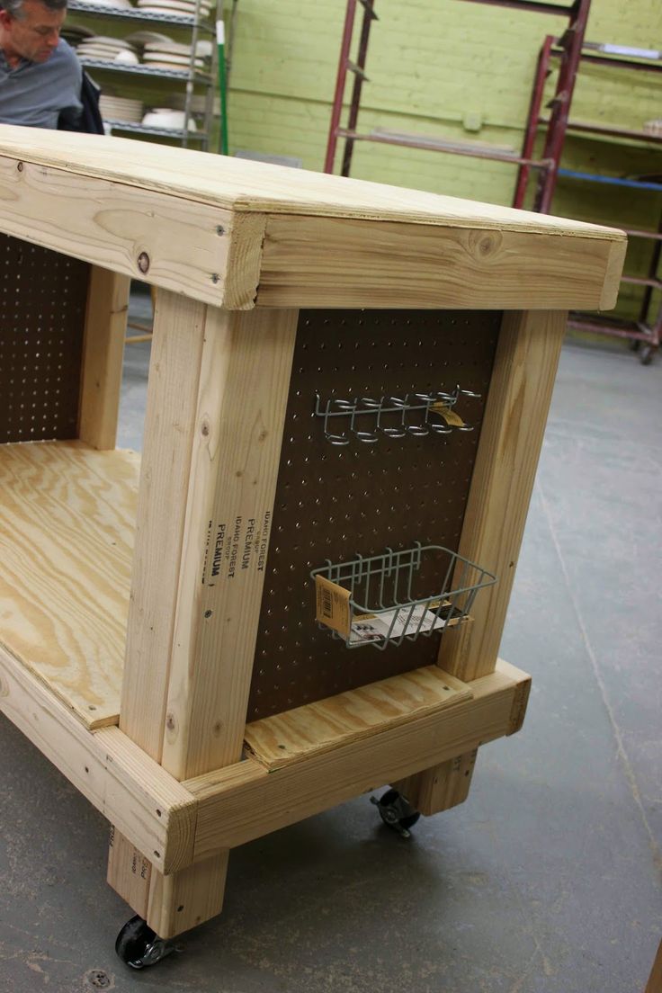 a man working on a wooden cabinet in a shop with shelves and wire baskets attached to it