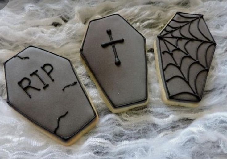 three decorated cookies sitting on top of a white cloth covered table next to each other