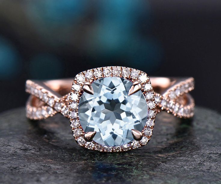 an engagement ring with a blue topazte surrounded by white and rose gold diamonds