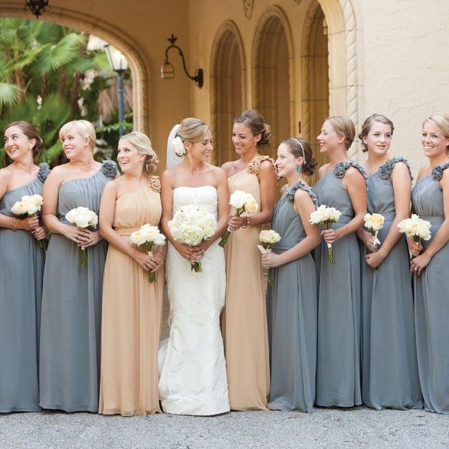 a group of women standing next to each other in front of a building holding bouquets