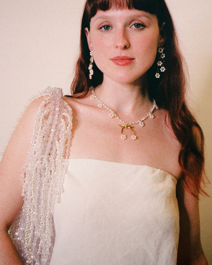 a woman in a white dress wearing pearls