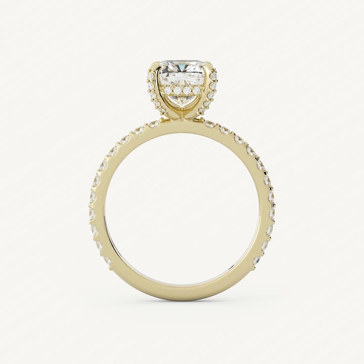 a yellow gold engagement ring with an oval cut diamond on the center and pave set shoulders