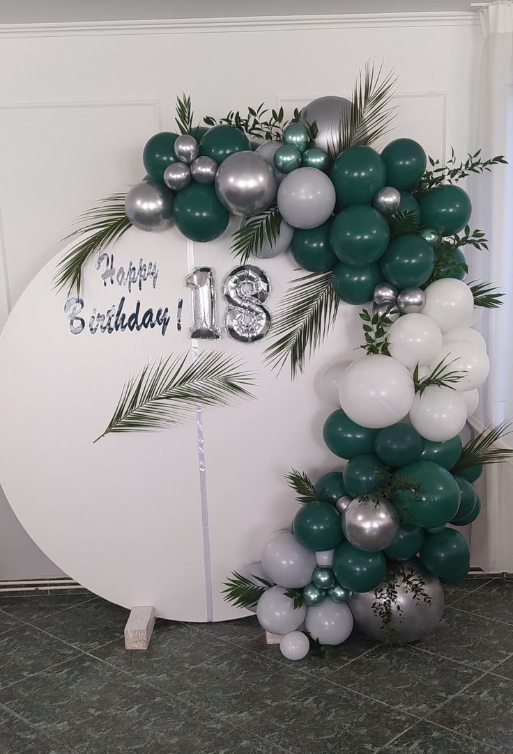 the balloon arch is decorated with green and silver balloons