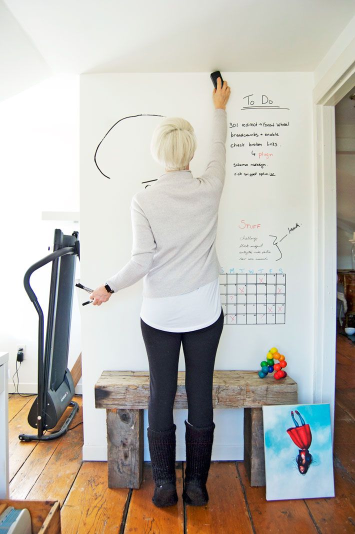 a woman writing on a whiteboard next to a wooden bench and exercise equipment in the background