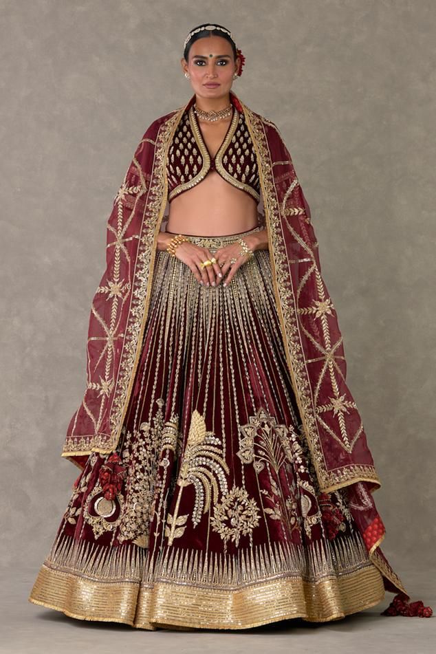 Wine lehenga with separate cancan skirt, adorned with Dil-chidiya, Kalpataru motifs in dori, zari, moti and sitara kaam and hemline is embellished with beautiful sitara border and edged with jhallar. Paired with V neck embroidered padded blouse and border embroidered dupatta.
Components: 4
Pattern: Embellished, Embroidery
Type Of Work: Dori, zari, moti
Neckline: V neck
Sleeve Type: Half sleeves
Fabric: Lehenga and Blouse: Silk Velvet, Dupatta: Silk Organza
Color: Wine
Other Details: 
Inverted V Can Can Skirt, Wine Lehenga, Cancan Skirt, Embellished Embroidery, Lehenga And Blouse, Velvet Dupatta, Caribbean Fashion, Celebrity Bride, Unconventional Wedding Dress