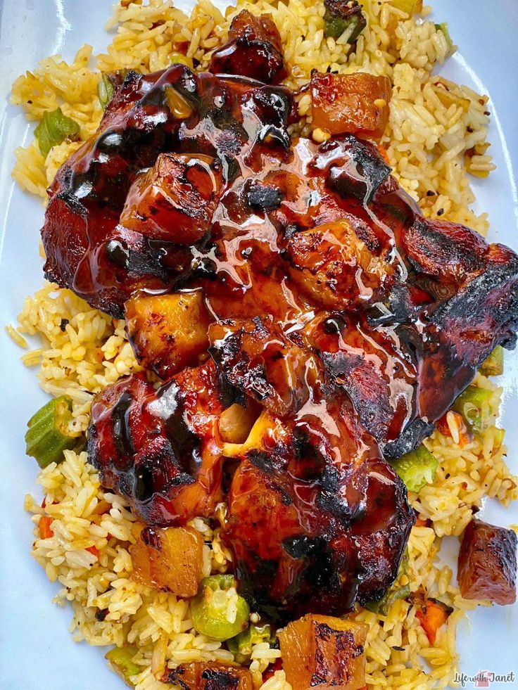 a white plate topped with rice and meat covered in bbq sauce on top of it