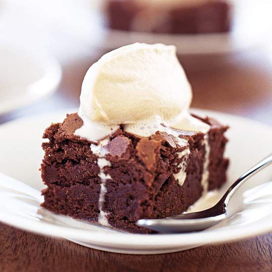 a piece of chocolate cake with ice cream on top is sitting on a white plate