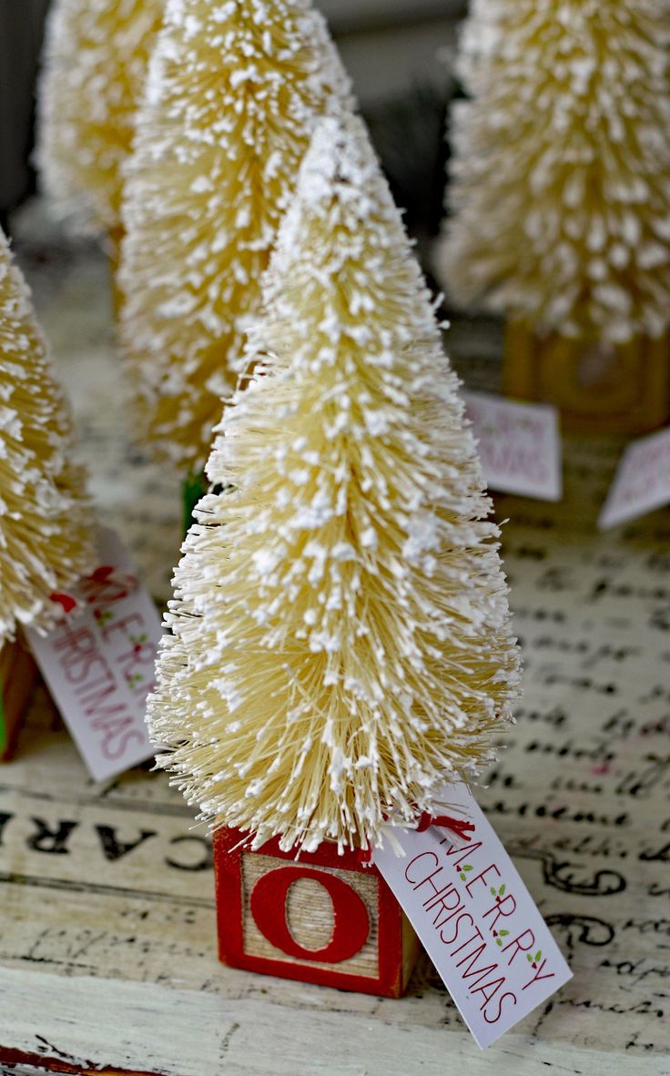 small white christmas trees with tags on them sitting in front of an old typewriter