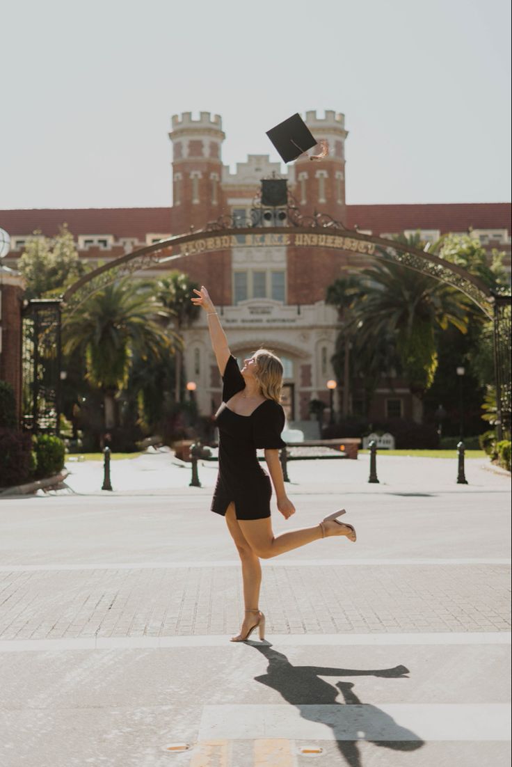 a woman in black shirt and shorts jumping up into the air with a book above her head