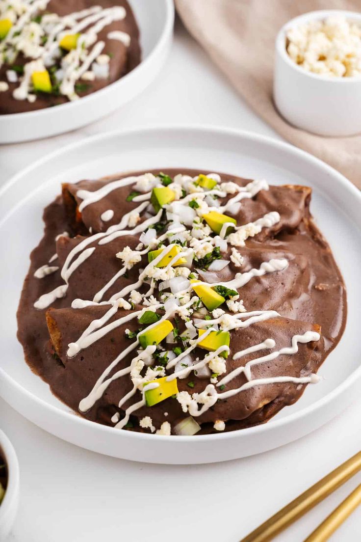 two white plates topped with chocolate pudding and sprinkled with toppings next to bowls of popcorn