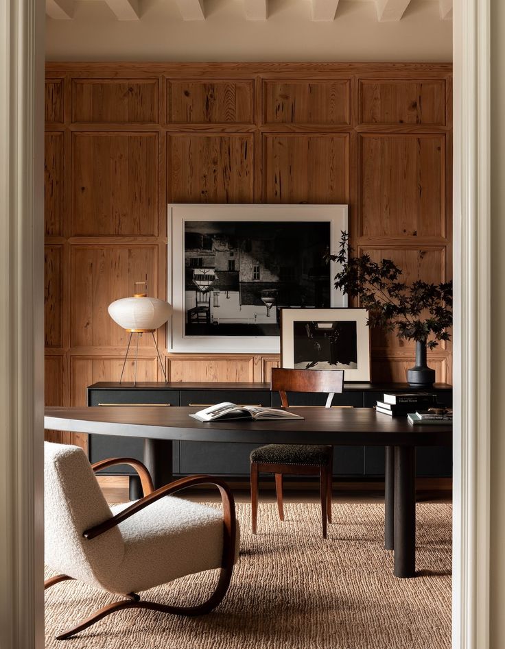 an office with wood paneling and chairs in the corner, along with a large desk