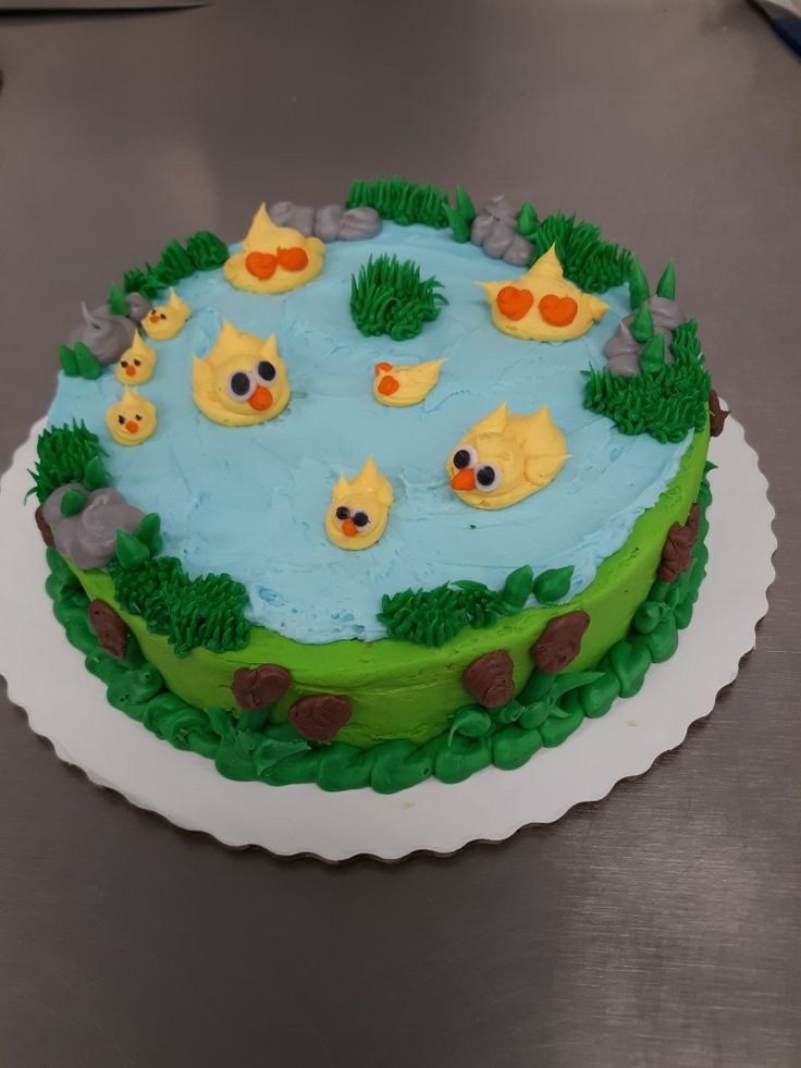 a cake decorated with ducks and grass in the shape of a pond on top of a table