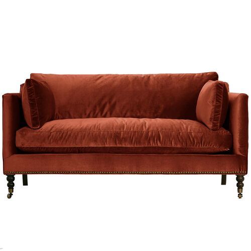 an orange velvet couch with wooden legs