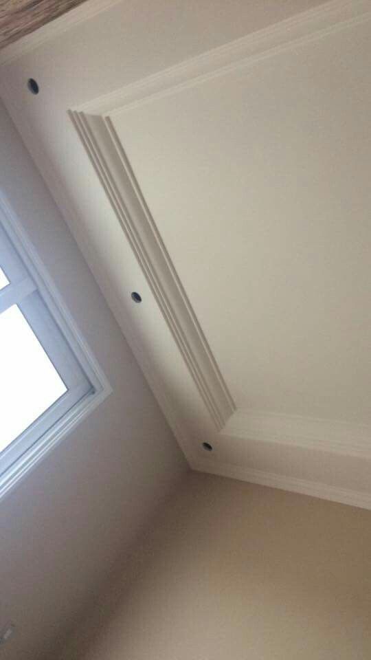 the corner of a room with a skylight and white paint on the ceiling,