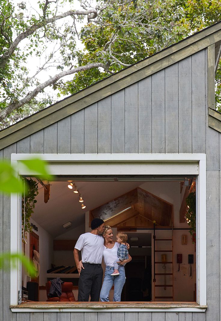 a man and woman are standing in the open window of a tiny house with their child