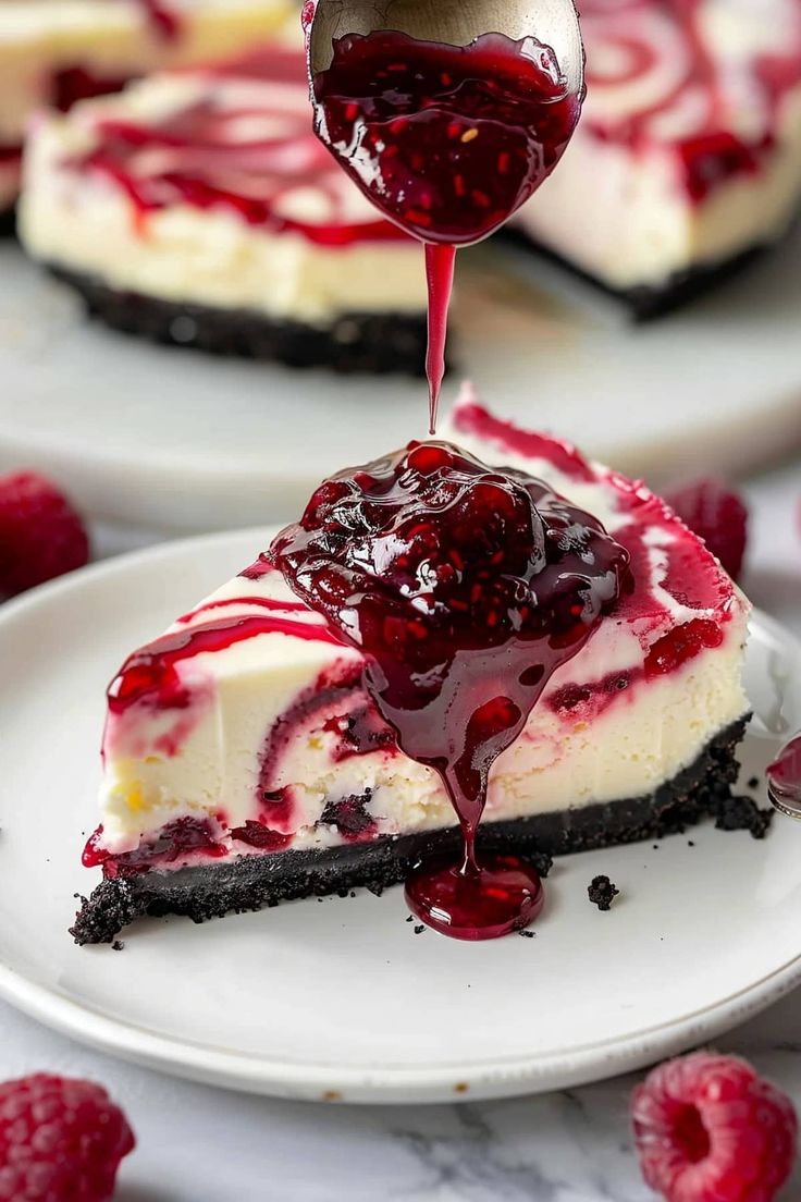 a slice of cheesecake with raspberry sauce being drizzled over it