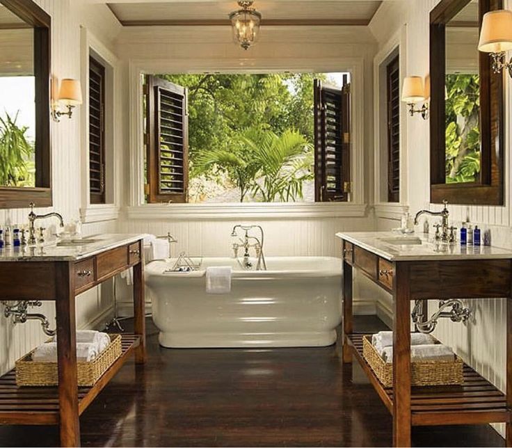 a bathroom with two sinks and a bathtub in the middle, surrounded by windows