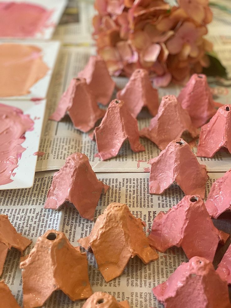 some pink and gold paint is on top of newspaper pages with flowers in the background