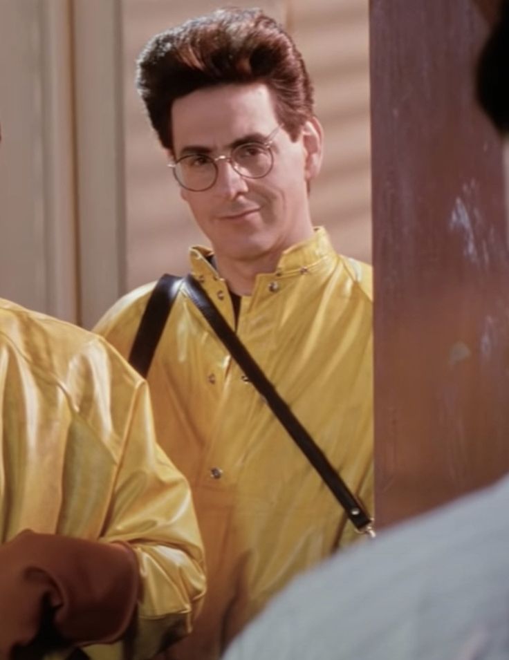 two men standing next to each other in front of a door wearing yellow shirts and glasses