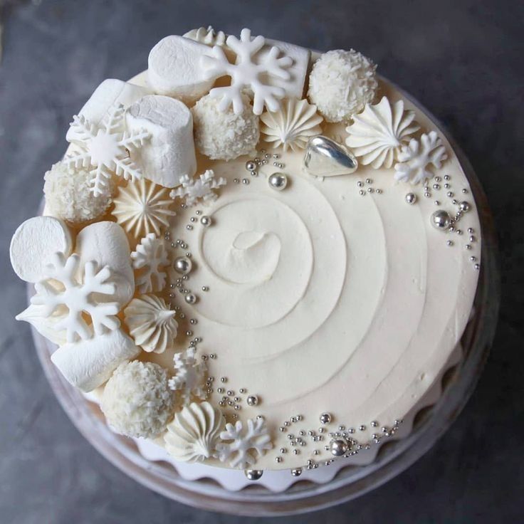 a cake with white frosting decorated with snowflakes and other decorations on top