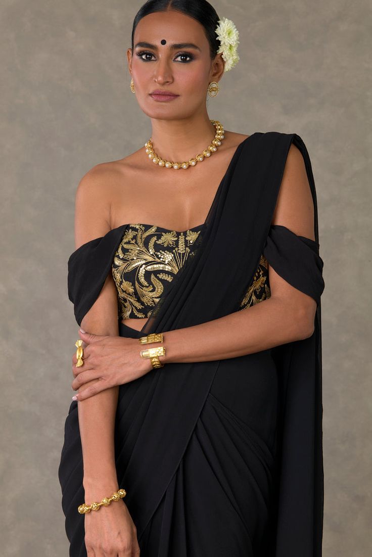 Embrace effortless elegance with a pre-stitched sari featuring a convenient side enclosure, adorned with a neel-kamal border in dori and sitara kaam, complemented by a pinstripe gold foil finish at the back. The ensemble is completed with an off-shoulder bustier showcasing cowl sleeves and intricate jhaal in dori and sitara kaam, enhanced with a center back closure. Revel in the contemporary sophistication of this stylish and convenient ensemble Sitara Work, Saree Georgette, Drape Saree, Black Saree, Indian Fashion Designers, Sequins Embroidery, Blouse Online, Raw Silk, Aza Fashion