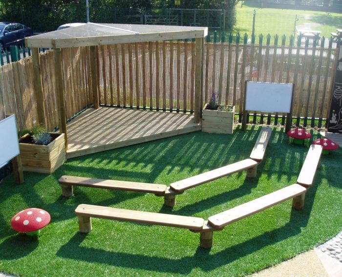 an outdoor play area with wooden benches and grass