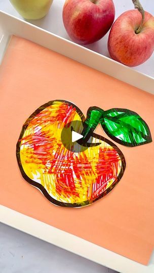 an apple painted on a tray next to apples