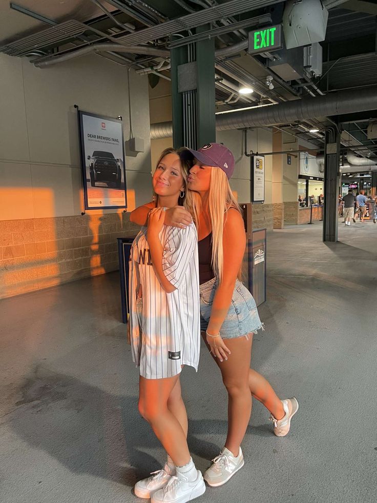 two young women standing next to each other near a train station platform with an exit sign in the background