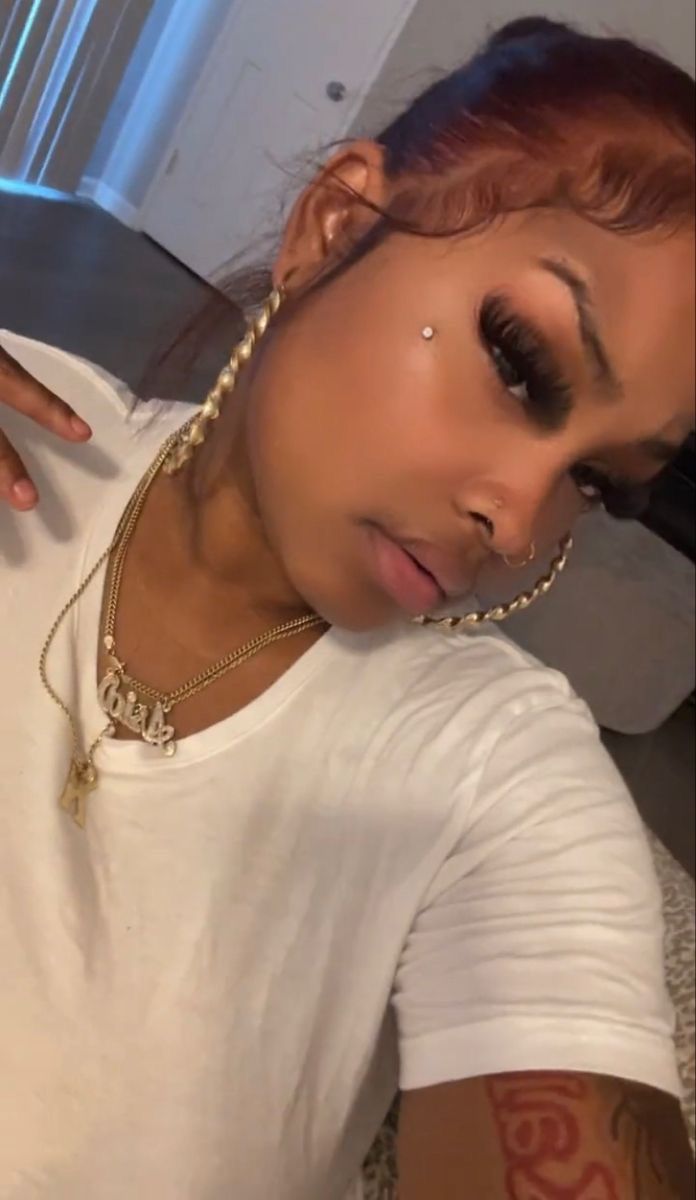 a close up of a person wearing a white shirt and gold chains on her neck