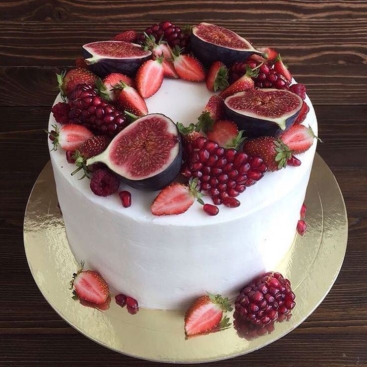 a white cake topped with fresh fruit on top of a wooden table