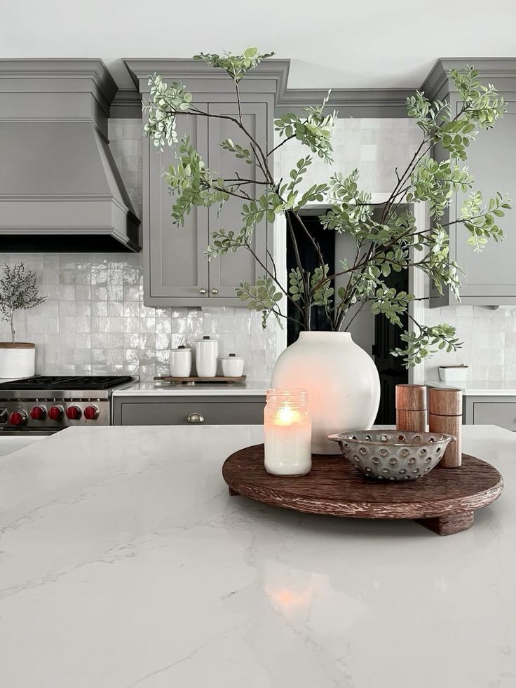 a candle is sitting on a tray in the middle of a kitchen counter with gray cabinets